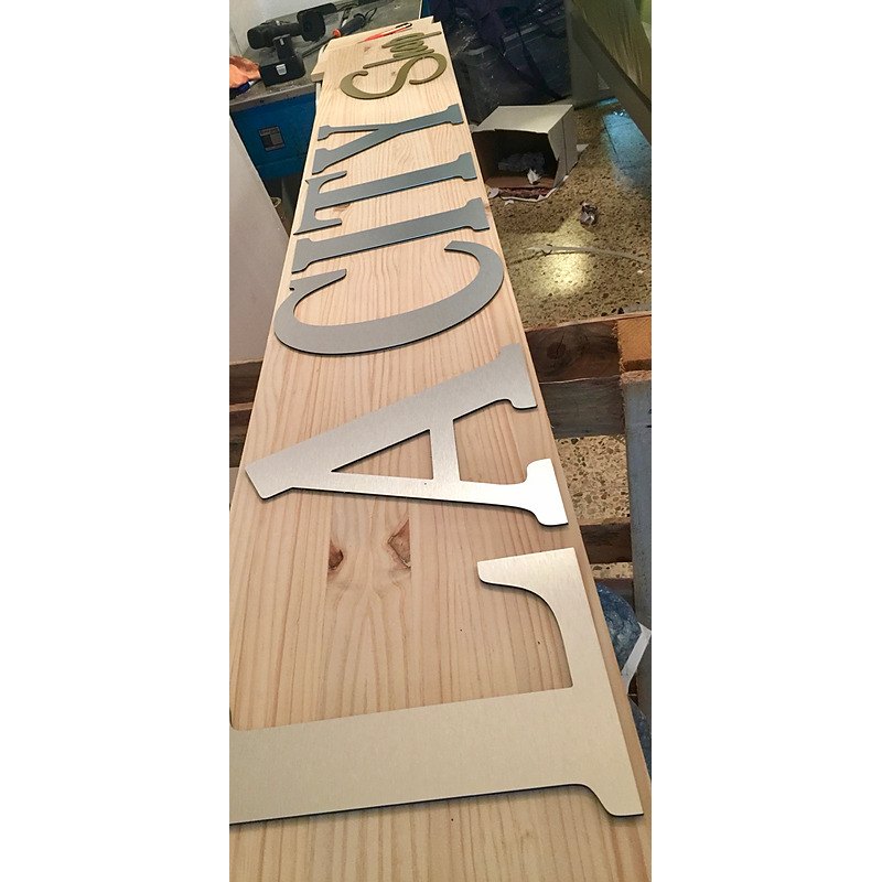 Rótulo de madera con letras metálicas para comercio.
